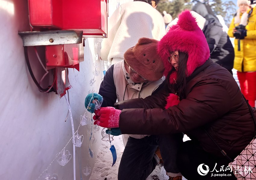 一對戀人雪花風(fēng)鈴掛于美人松寄情壁上。人民網(wǎng)記者 關(guān)思聰攝